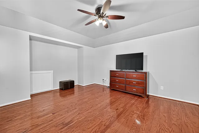 an empty room with wooden floor closet and windows