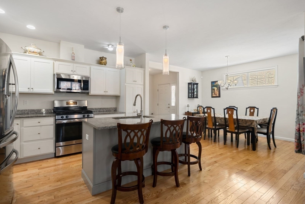44 Mariners Way, Unit 44 Plymouth, MA 02360 - Photo 4 of 36 a large kitchen with stainless steel appliances granite countertop a stove a sink a dining table and chairs