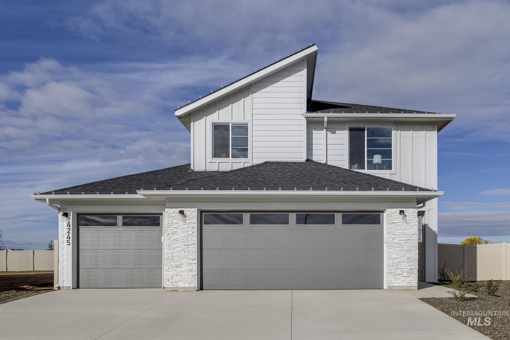 View of front of home featuring stone siding, roof with shingles, board and batten siding, and driveway