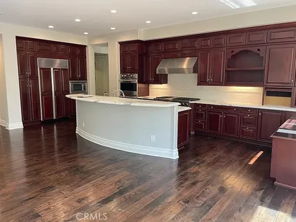 an open kitchen with wooden floor and stainless steel appliances