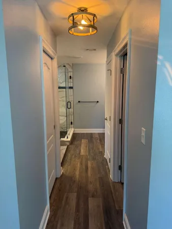 a view of a hallway with wooden floor and a bathroom