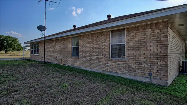a view of a house with a yard and a large tree