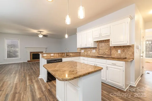 a kitchen with a sink dishwasher a stove a microwave oven and a dining table with wooden floor