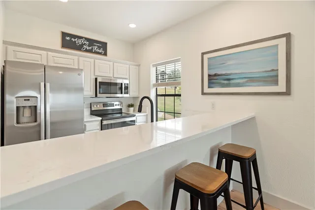 a kitchen with stainless steel appliances kitchen island a refrigerator and a chair