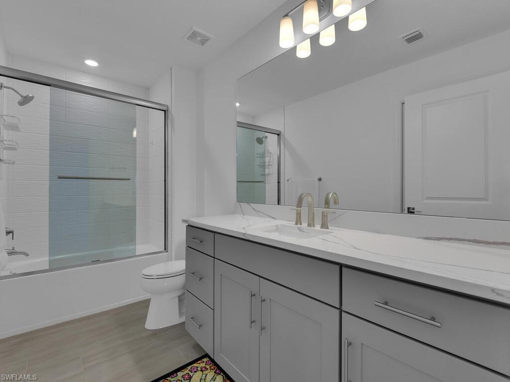 7229 Wiregrass Court Naples, FL 34114 - Photo 33 of 40 a bathroom with a granite countertop sink a toilet and shower