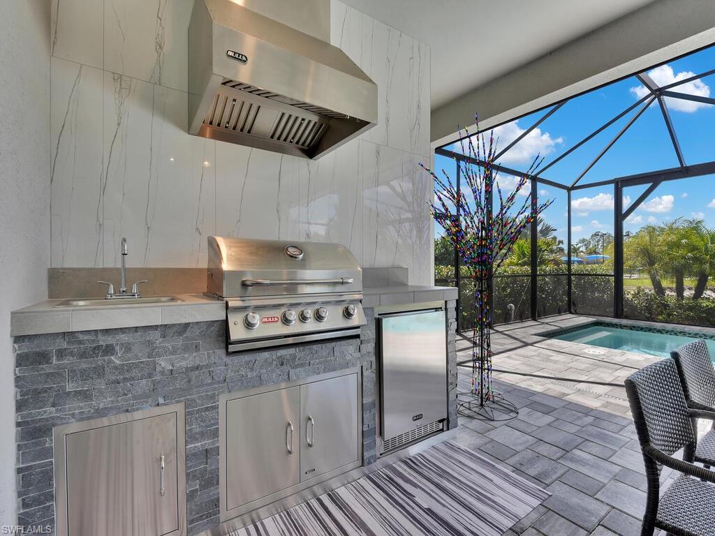 7229 Wiregrass Court Naples, FL 34114 - Photo 37 of 40 a kitchen with stainless steel appliances granite countertop a stove a sink and a refrigerator