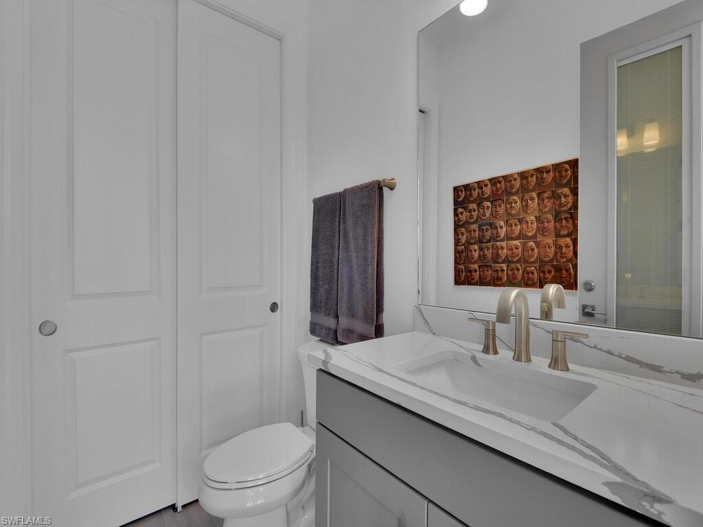 7229 Wiregrass Court Naples, FL 34114 - Photo 38 of 40 a bathroom with a granite countertop sink a toilet and a shower