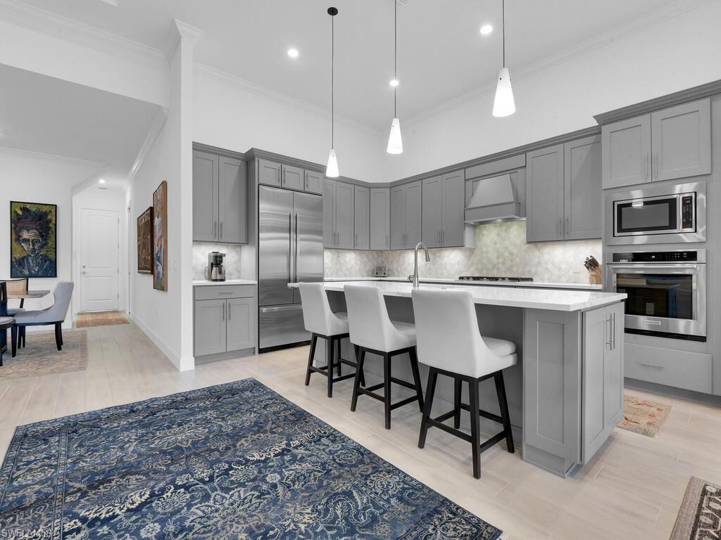 7229 Wiregrass Court Naples, FL 34114 - Photo 7 of 40 a large kitchen with kitchen island a dining table and chairs