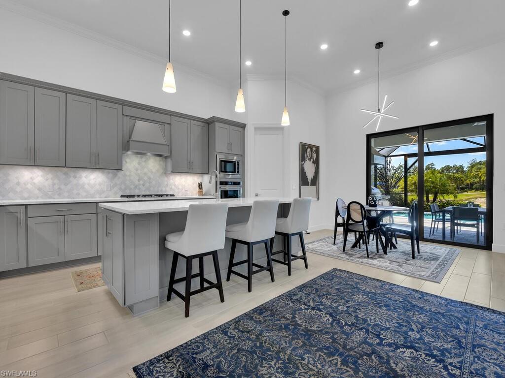 7229 Wiregrass Court Naples, FL 34114 - Photo 8 of 40 a large kitchen with kitchen island a dining table chairs and white cabinets