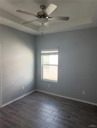 an empty room with wooden floor fan and windows