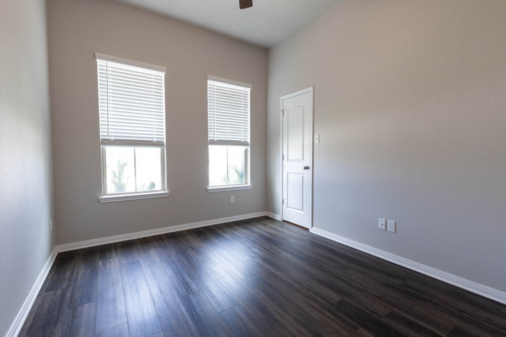 1001 Rootstock Rd. Brenham, TX 77833 - Photo 17 of 28 an empty room with wooden floor and windows