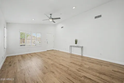 an empty room with wooden floor cabinet and windows