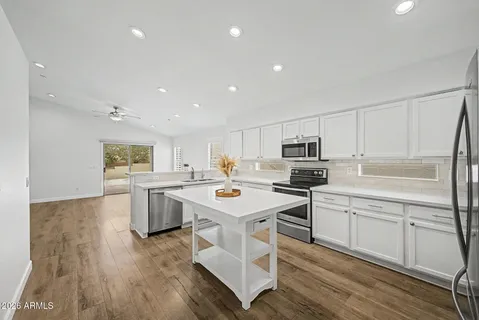 a kitchen with stainless steel appliances a stove a sink dishwasher a refrigerator and white cabinets with wooden floor