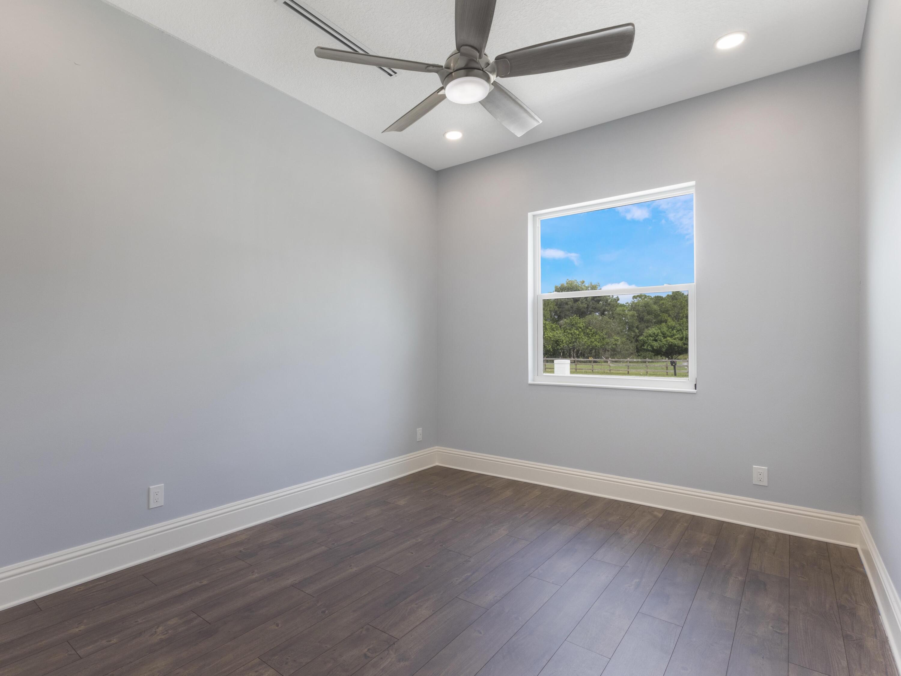17436 71st Lane North Loxahatchee, FL 33470 - Photo 37 of 50 an empty room with wooden floor ceiling fan and windows