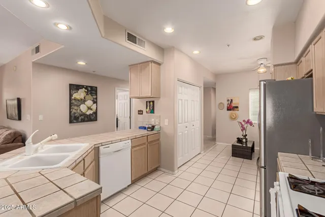 a large white kitchen with a refrigerator a sink dishwasher a stove and a dining table with wooden floor