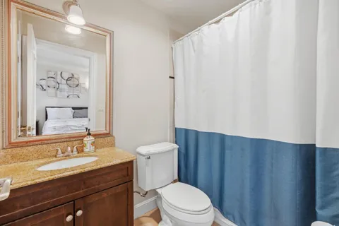 a bathroom with a granite countertop sink toilet and a mirror