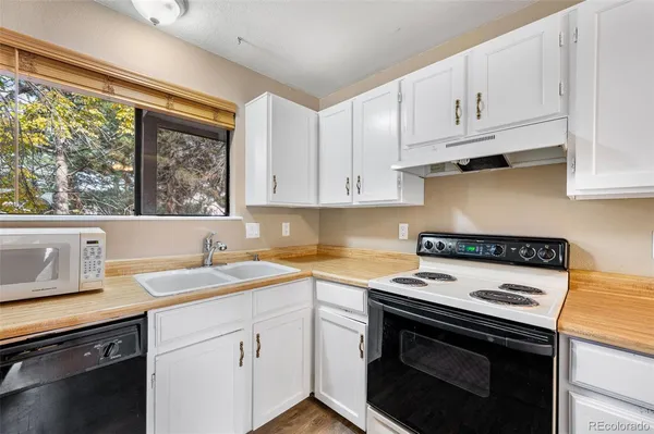 a kitchen with stainless steel appliances granite countertop a sink and cabinets with wooden floor