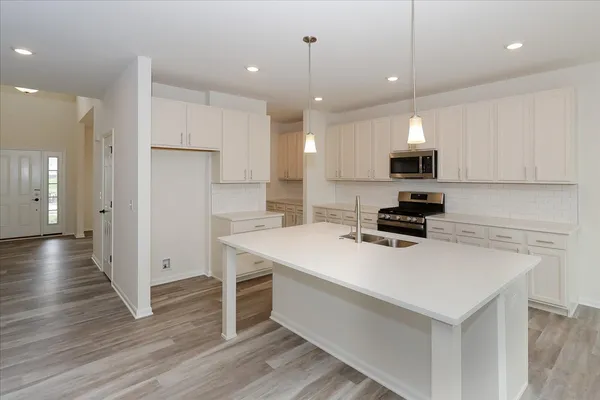 a kitchen with kitchen island a white counter top space cabinets and stainless steel appliances