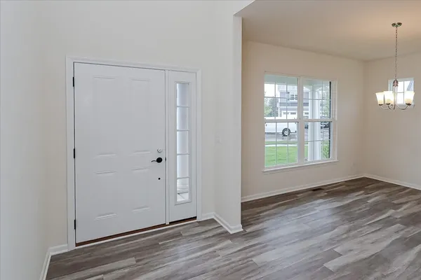a view of an empty room with window and wooden floor