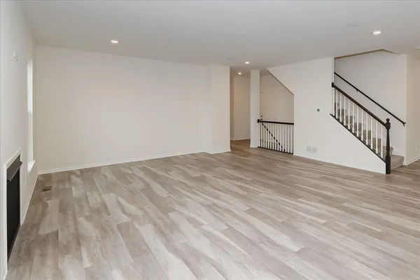 a view of an empty room with wooden floor and stairs