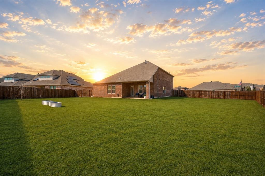 9828 Quail Pointe Road Aubrey, TX 76227 - Photo 20 of 23 Expansive green lawn, brick exterior with covered patio, and wood privacy fencing