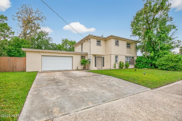 a view of a white house with a yard and large tree