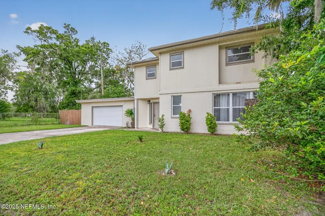 a front view of a house with a yard and trees