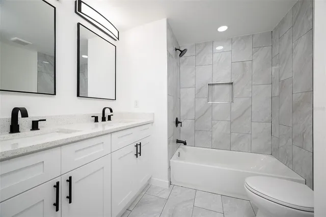 a bathroom with a double vanity sink toilet mirror and bathtub