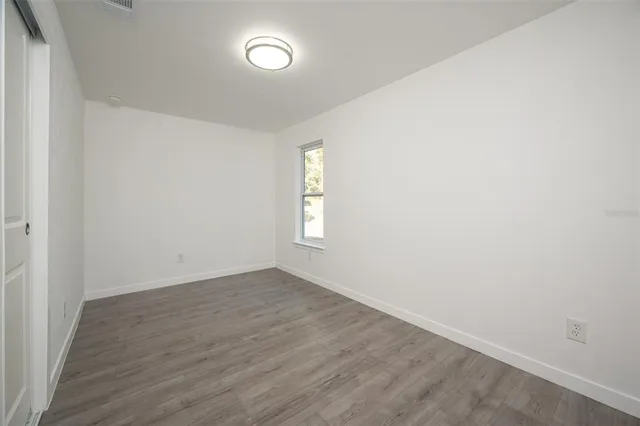 an empty room with wooden floor and window