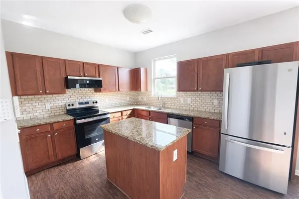 a kitchen with a refrigerator stove top oven a sink and dishwasher with wooden floor
