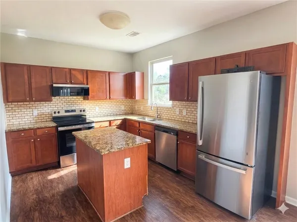 a kitchen with granite countertop a refrigerator stove top oven and sink