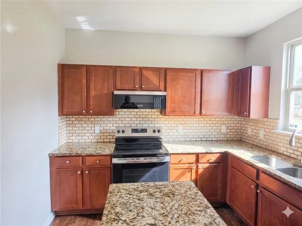 a kitchen with granite countertop wooden cabinets and a stove top oven