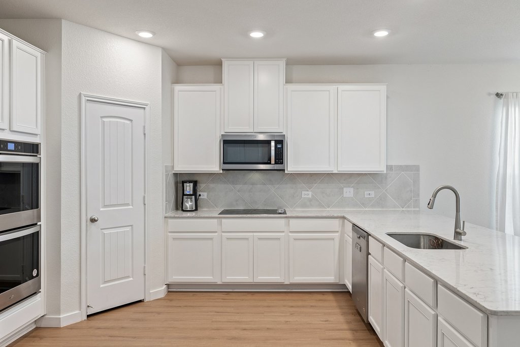 1926 Dragonfly Loop Bastrop, TX 78602 - Photo 7 of 32 a kitchen with stainless steel appliances granite countertop a sink and a stove top oven with wooden floor