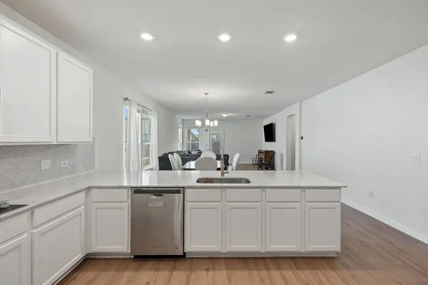 a kitchen with stainless steel appliances granite countertop a sink and a stove top oven with wooden floor