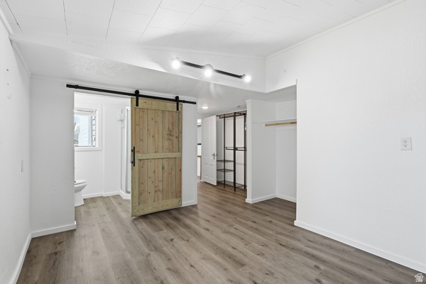 25615 Main Street Portage, UT 84331 - Photo 17 of 42 Unfurnished bedroom featuring a barn door, wood finished floors, crown molding, and ensuite bath