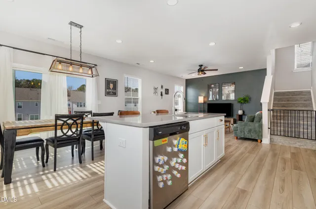 a kitchen with stainless steel appliances granite countertop a stove top oven a refrigerator a dining table and chairs with wooden floor