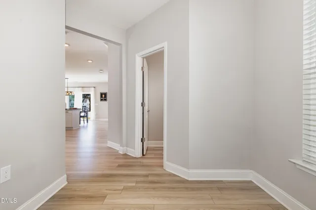 a view of a hallway with wooden floor windows and a kitchen