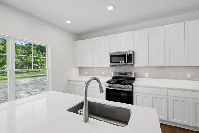 a kitchen with granite countertop white cabinets and stainless steel appliances