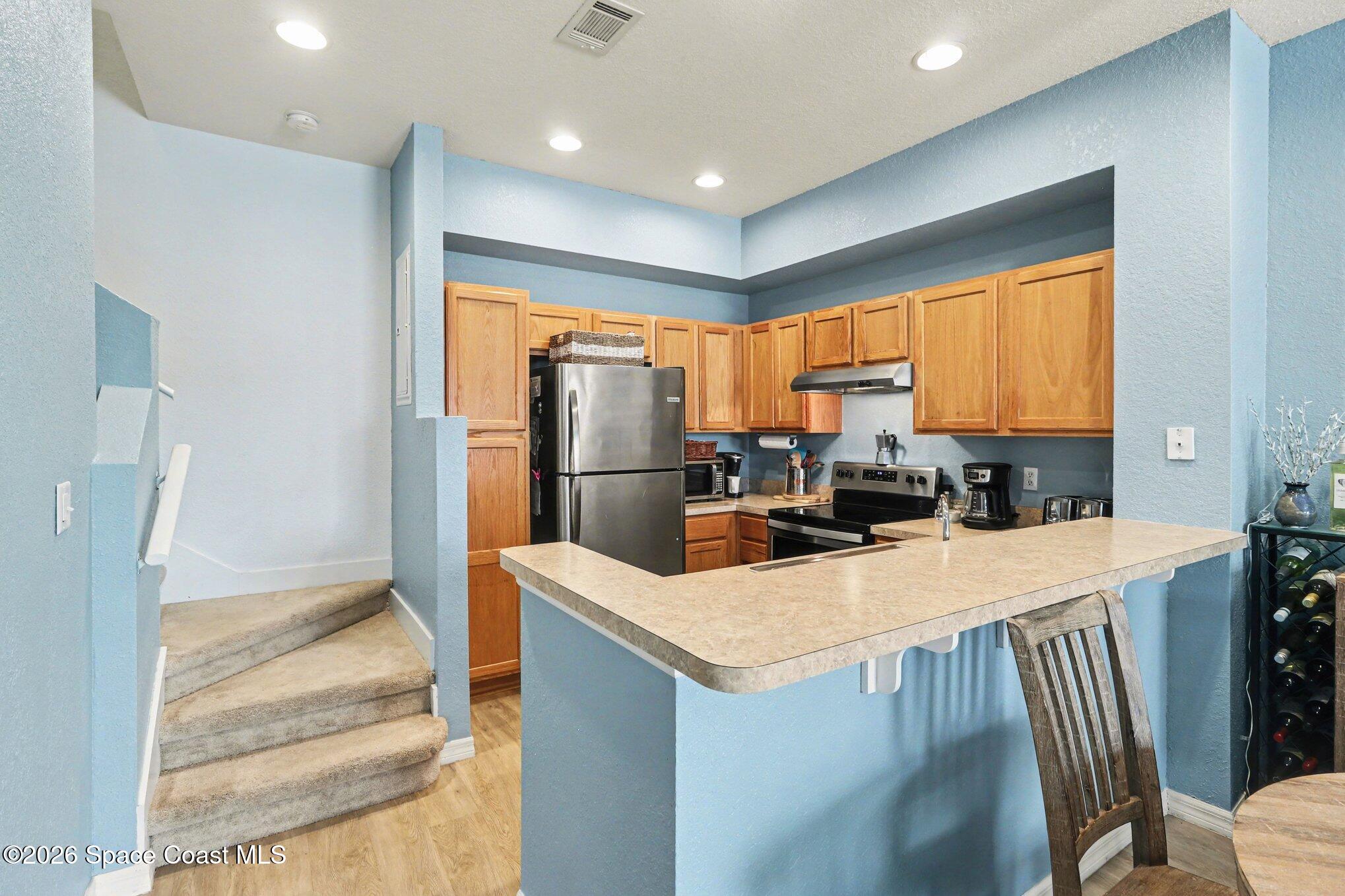 3955 Almeida Court, Unit 103 Melbourne, FL 32901 - Photo 13 of 32 a kitchen with stainless steel appliances a refrigerator a stove a sink dishwasher and a dining table with wooden floor