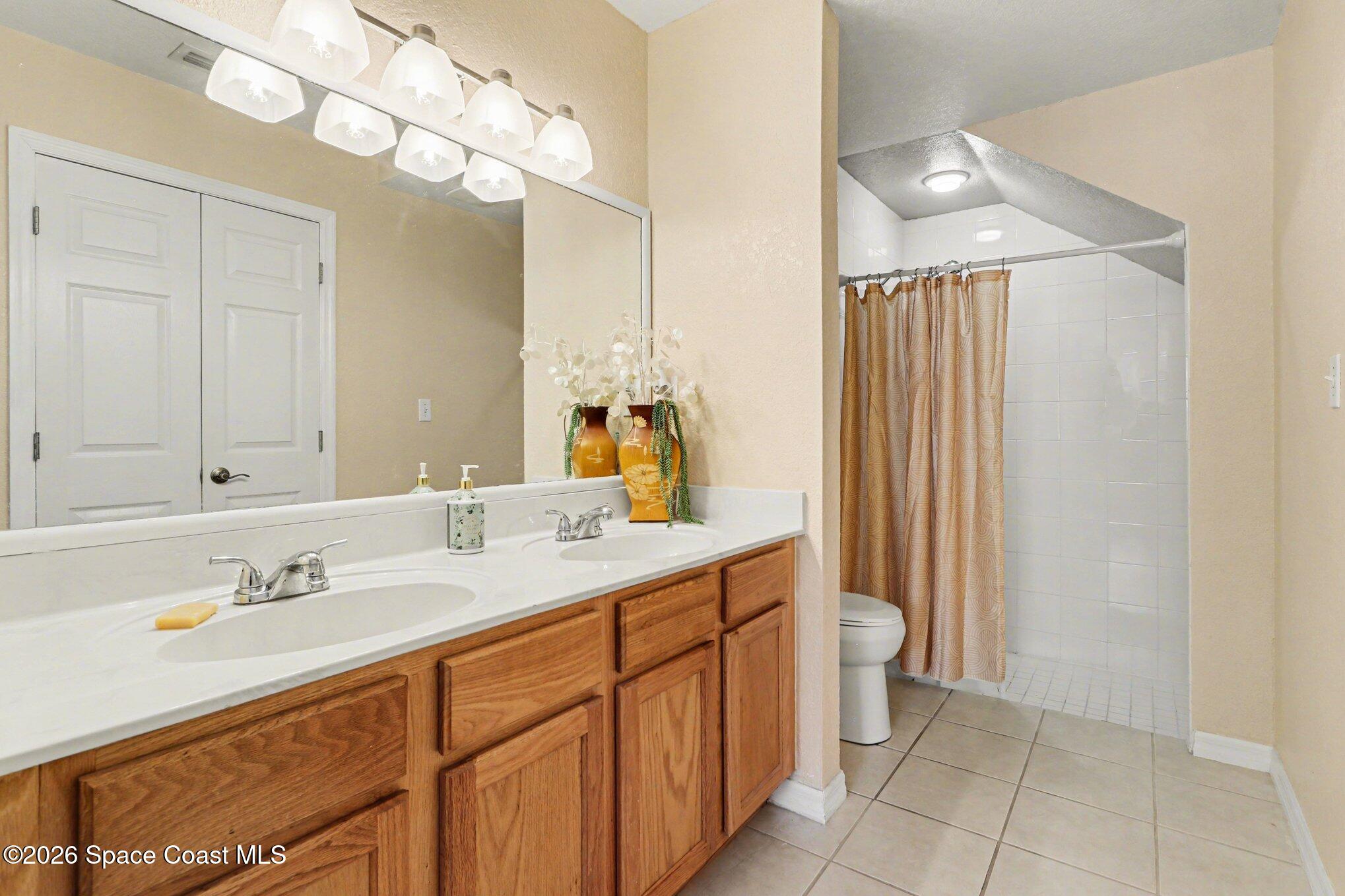 3955 Almeida Court, Unit 103 Melbourne, FL 32901 - Photo 18 of 32 a spacious bathroom with a double vanity sink and a mirror