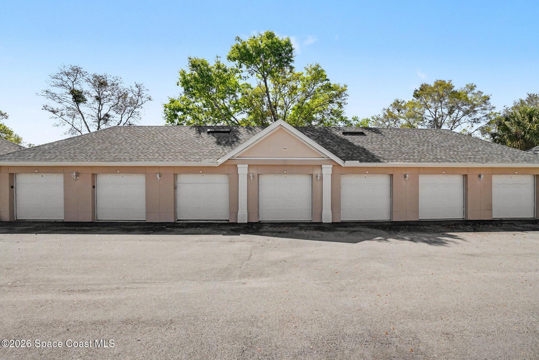 3955 Almeida Court, Unit 103 Melbourne, FL 32901 - Photo 30 of 32 a view of a white house with a big yard and large trees