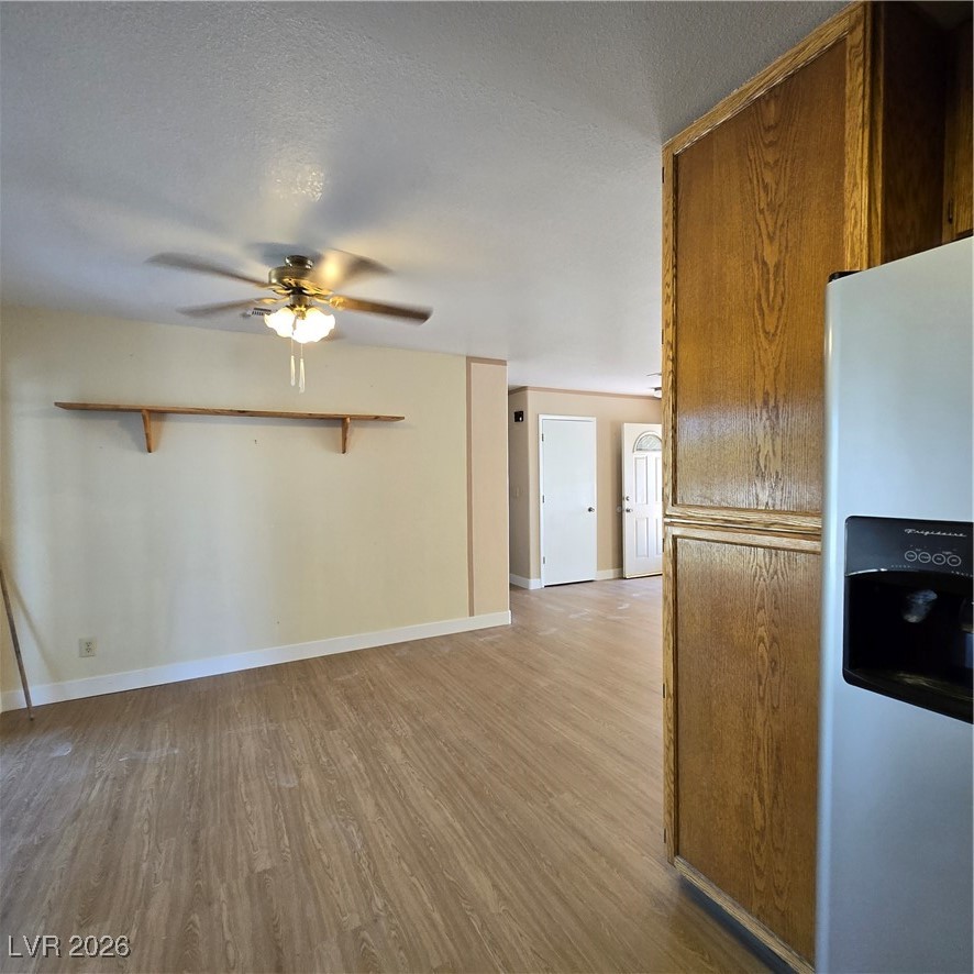 630 East Simkins Road Pahrump, NV 89060 - Photo 41 of 50 Kitchen featuring fridge, light wood finished floors, brown cabinetry, ceiling fan, and a textured ceiling