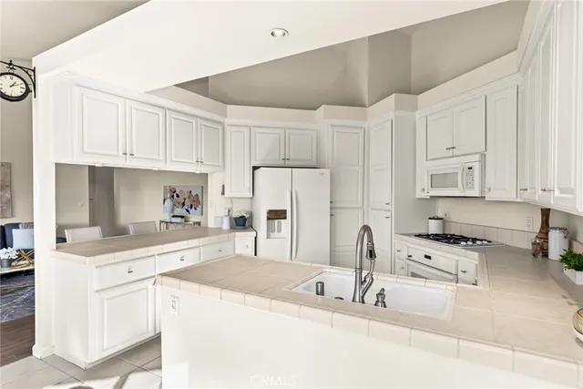 a kitchen with granite countertop a sink stainless steel appliances and white cabinets