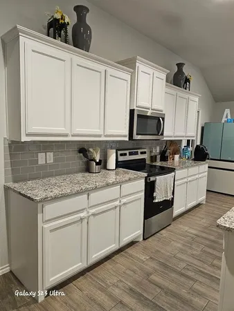 a kitchen with stainless steel appliances granite countertop a stove a sink and a microwave