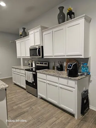 a kitchen with white cabinets and appliances