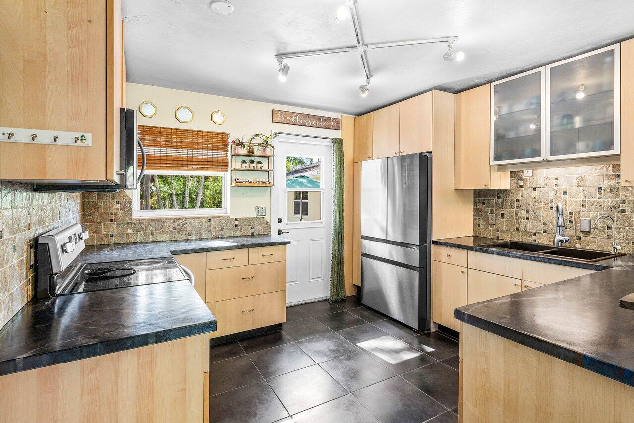 3064 Rostan Lane Palm Springs, FL 33461 - Photo 11 of 49 a kitchen with stainless steel appliances granite countertop a refrigerator a sink dishwasher a stove and white countertops with wooden floor