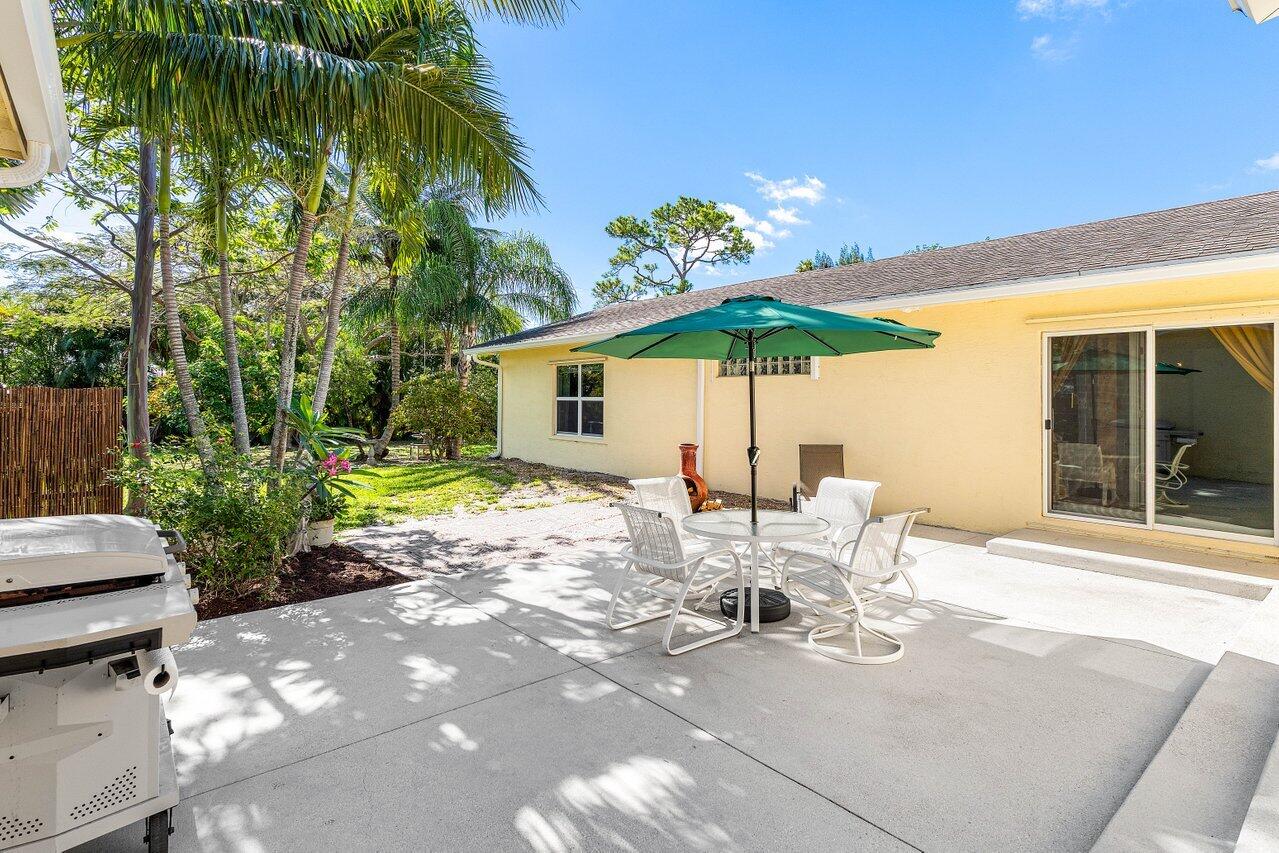 3064 Rostan Lane Palm Springs, FL 33461 - Photo 34 of 49 a view of a patio with table and chairs under an umbrella