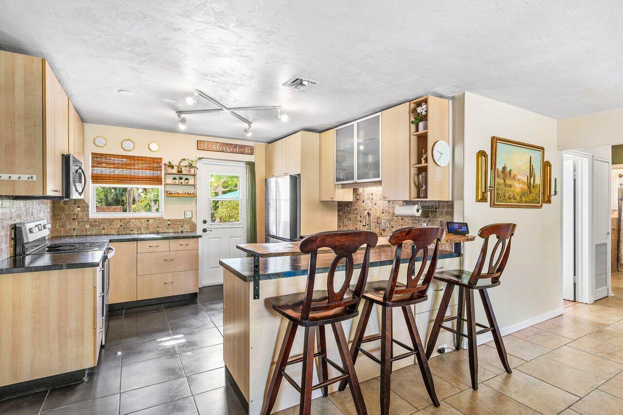 3064 Rostan Lane Palm Springs, FL 33461 - Photo 10 of 49 a kitchen with a table chairs sink and cabinets