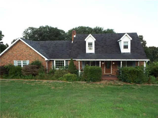 a view of a big house with a big yard plants and large trees