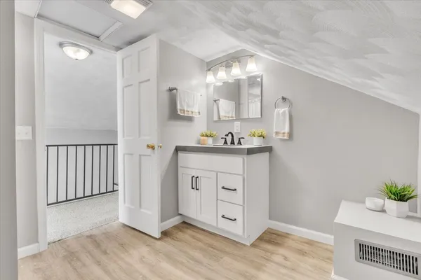 a bathroom with a sink a mirror and wooden floor